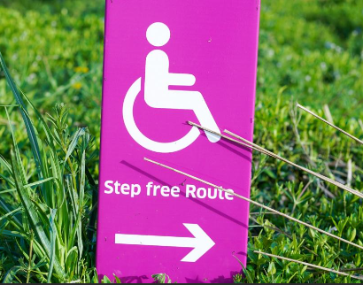 A pink sign with the symbol for disability and an arrow labeled Step free route.